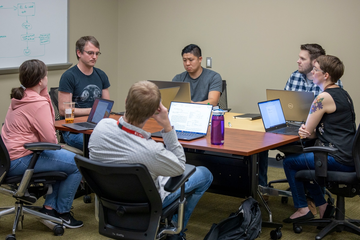 OC-ALC researchers sit at a table discussing their latest project