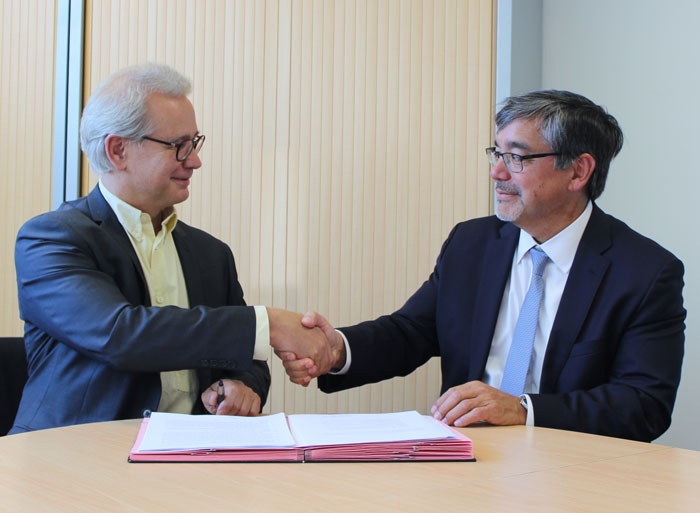 Two men shaking hands over a stack of documents