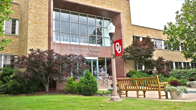 The front of the OU-Tulsa administrationg building, constructed of blonde brick and a terra cotta colored front section with Schusterman Center University of Oklahoma engraved