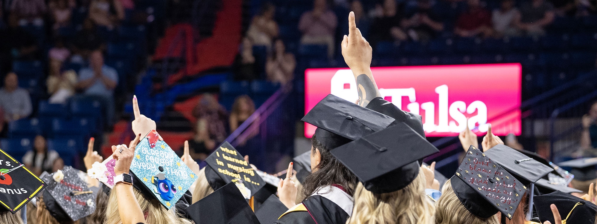 OU-Tulsa students in graduation regalia attending a commencement ceremony.