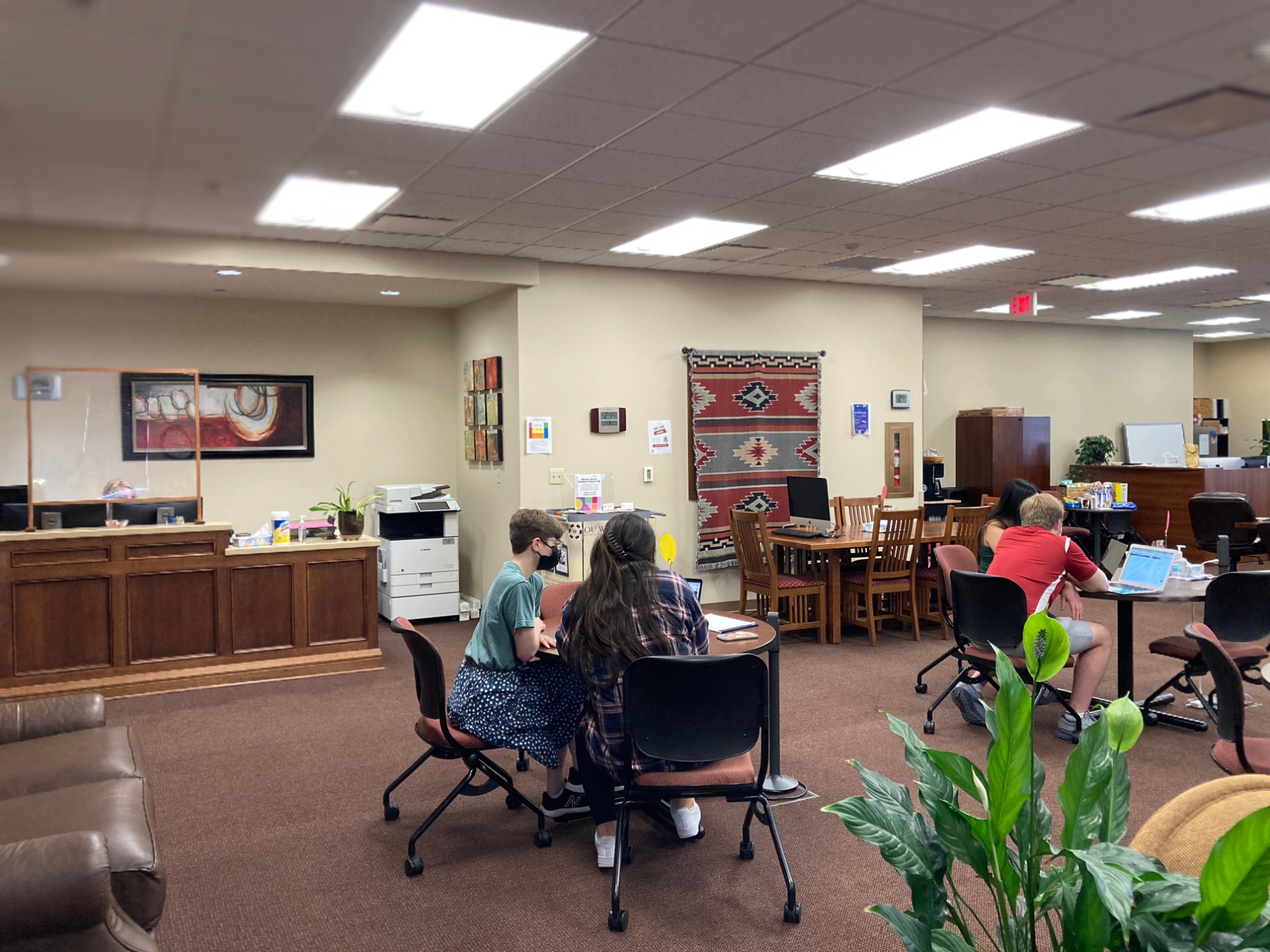 Students sitting at round tables in the Writing Center space.
